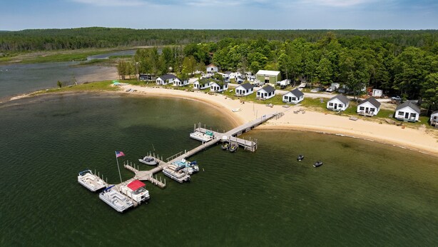 An aerial view of a lakeside vacation rental community with multiple houses, a dock, and boats. - Complimentary Boat Rentals! Lake Huron Cabin (Cedarville)
