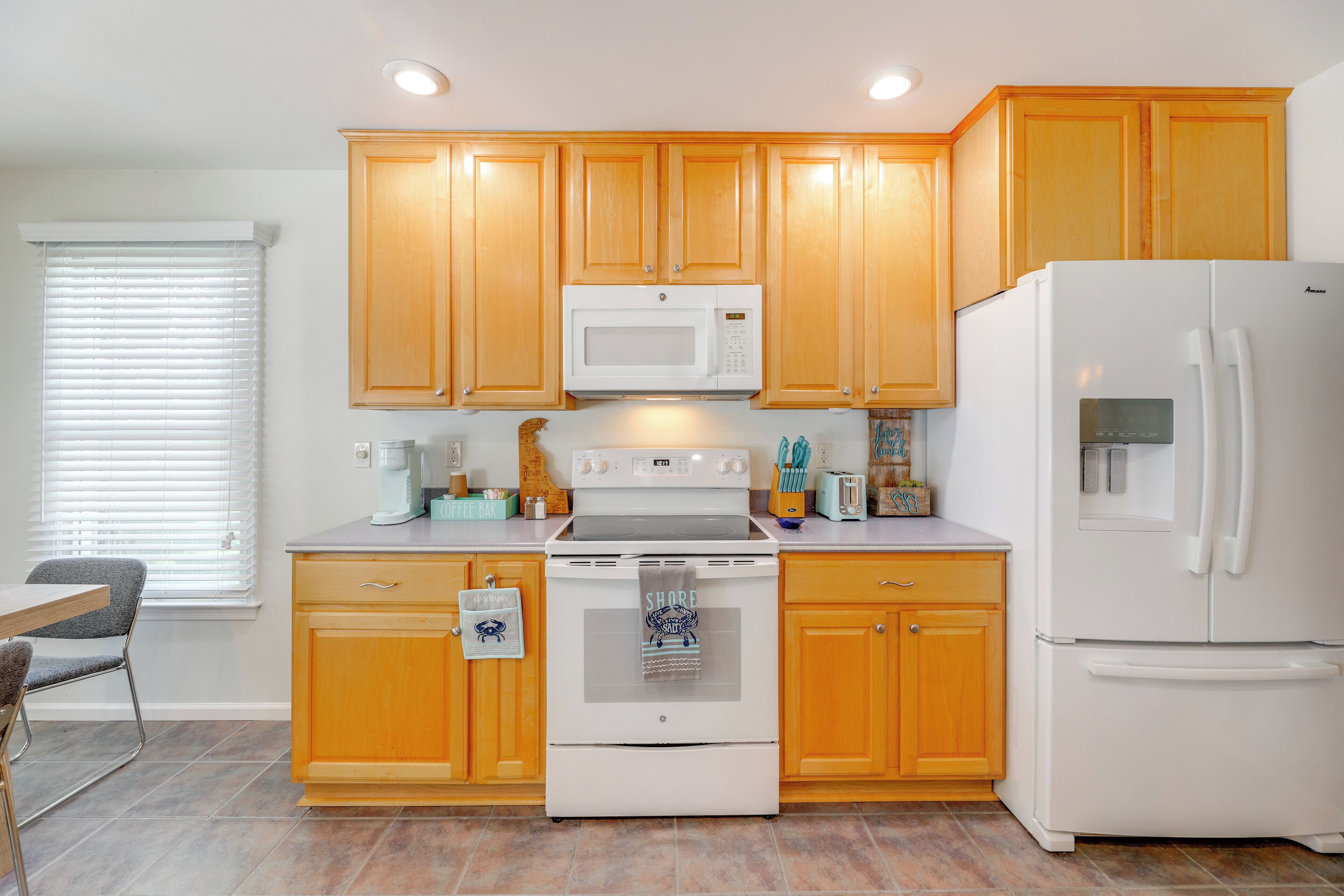 A kitchen with wooden cabinets, a white stove, a microwave, and a refrigerator.