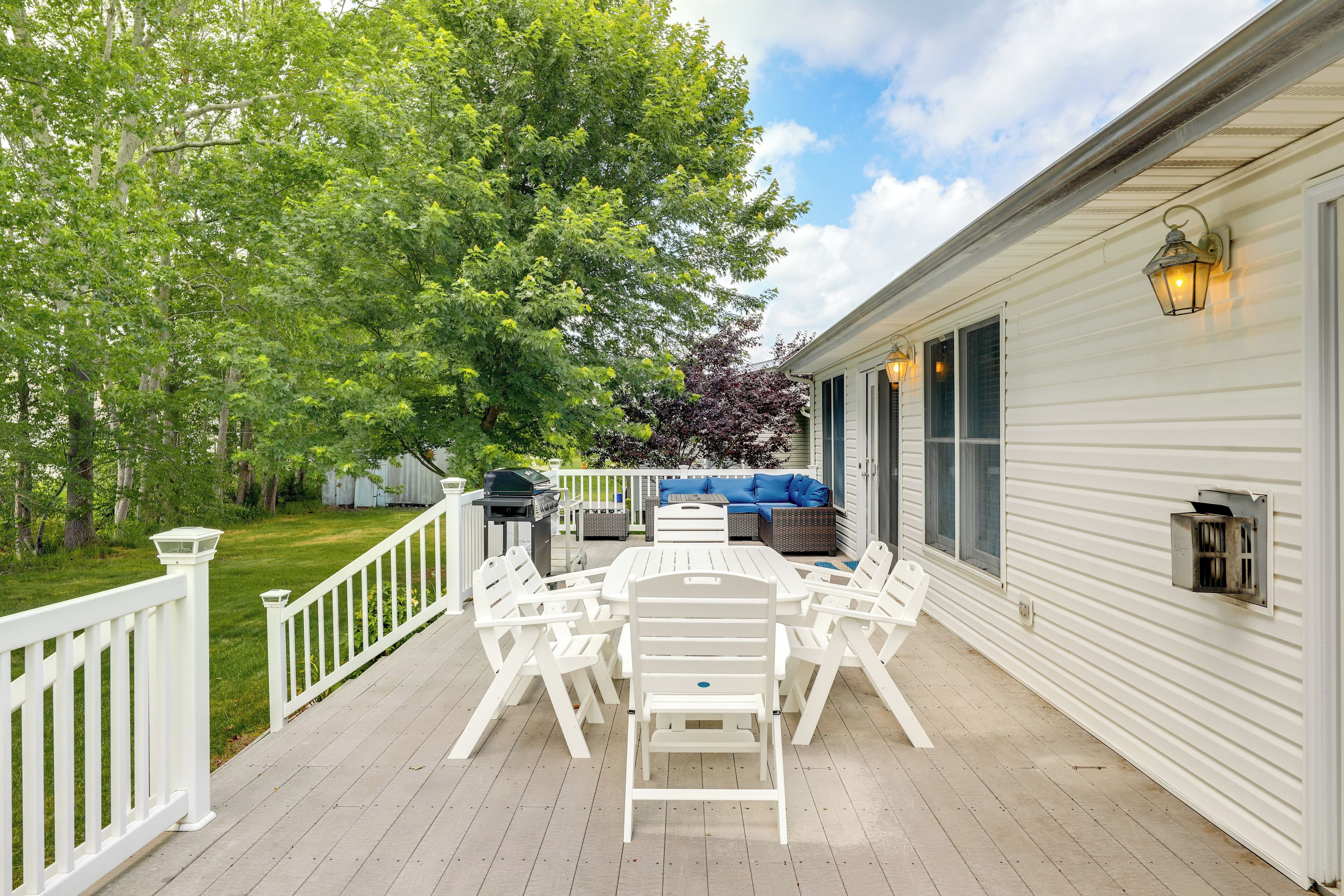 A covered patio with a white table and chairs, a grill, and a blue sofa.