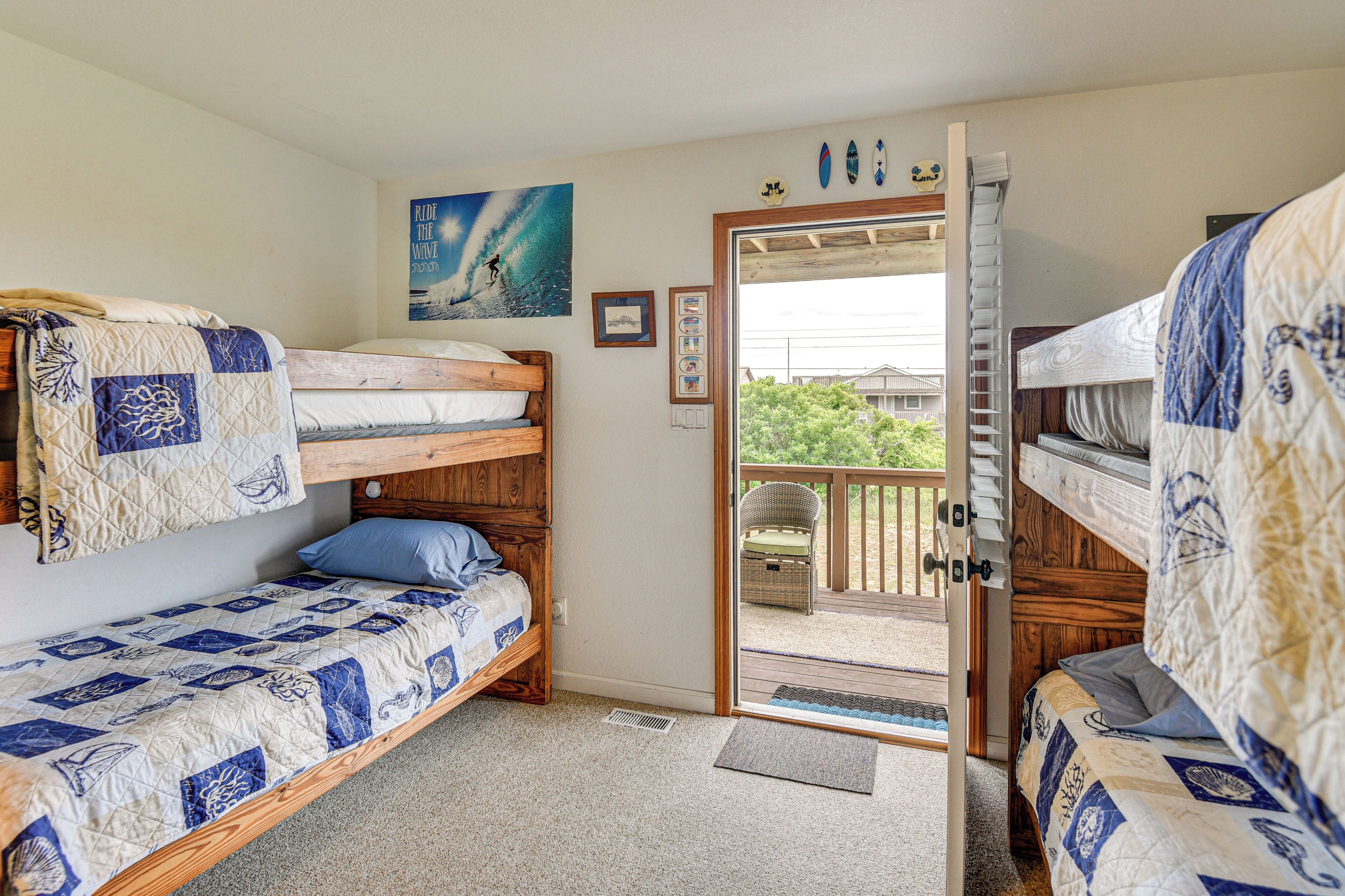 Una habitación con dos literas, una puerta que da a un espacio exterior y una decoración de tabla de surf en la pared.