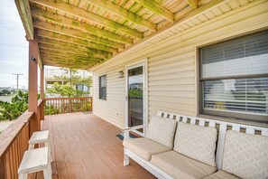 A covered porch with a wooden bench and a cushioned bench. - Walk to Beach + Restaurants: Outer Banks Retreat (Kill Devil Hills)