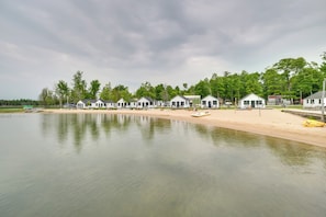 A row of white cabins with a sandy beach and a calm lake in the foreground. - Beachside Cabin w/ Views on Les Cheneaux Islands (Cedarville)