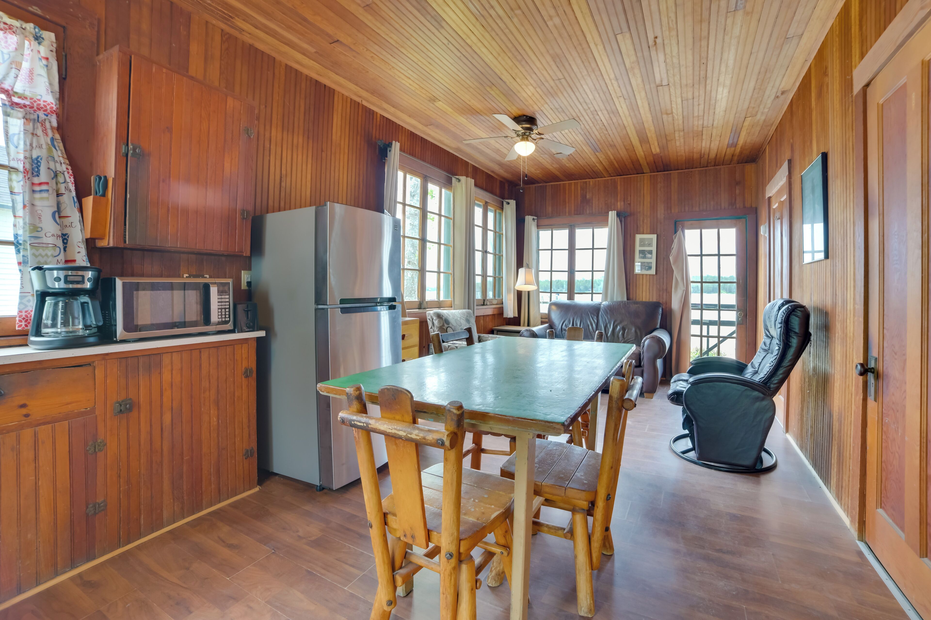 L’intérieur d’un chalet en bois comprend une table à manger, des chaises, un réfrigérateur, un four à micro-ondes et un fauteuil de massage.