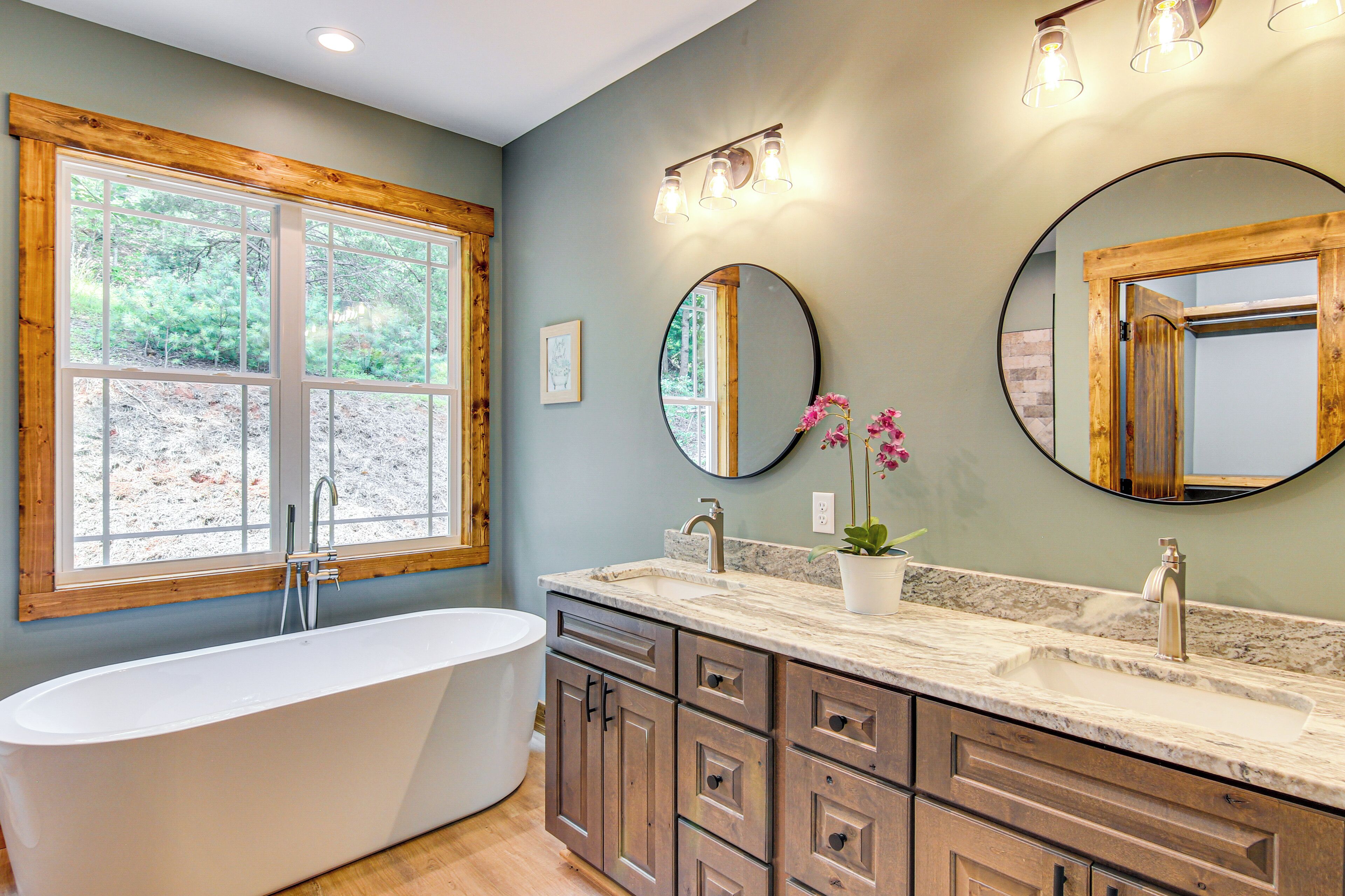 A bathroom with a freestanding bathtub, a double sink vanity, and two wall-mounted mirrors.