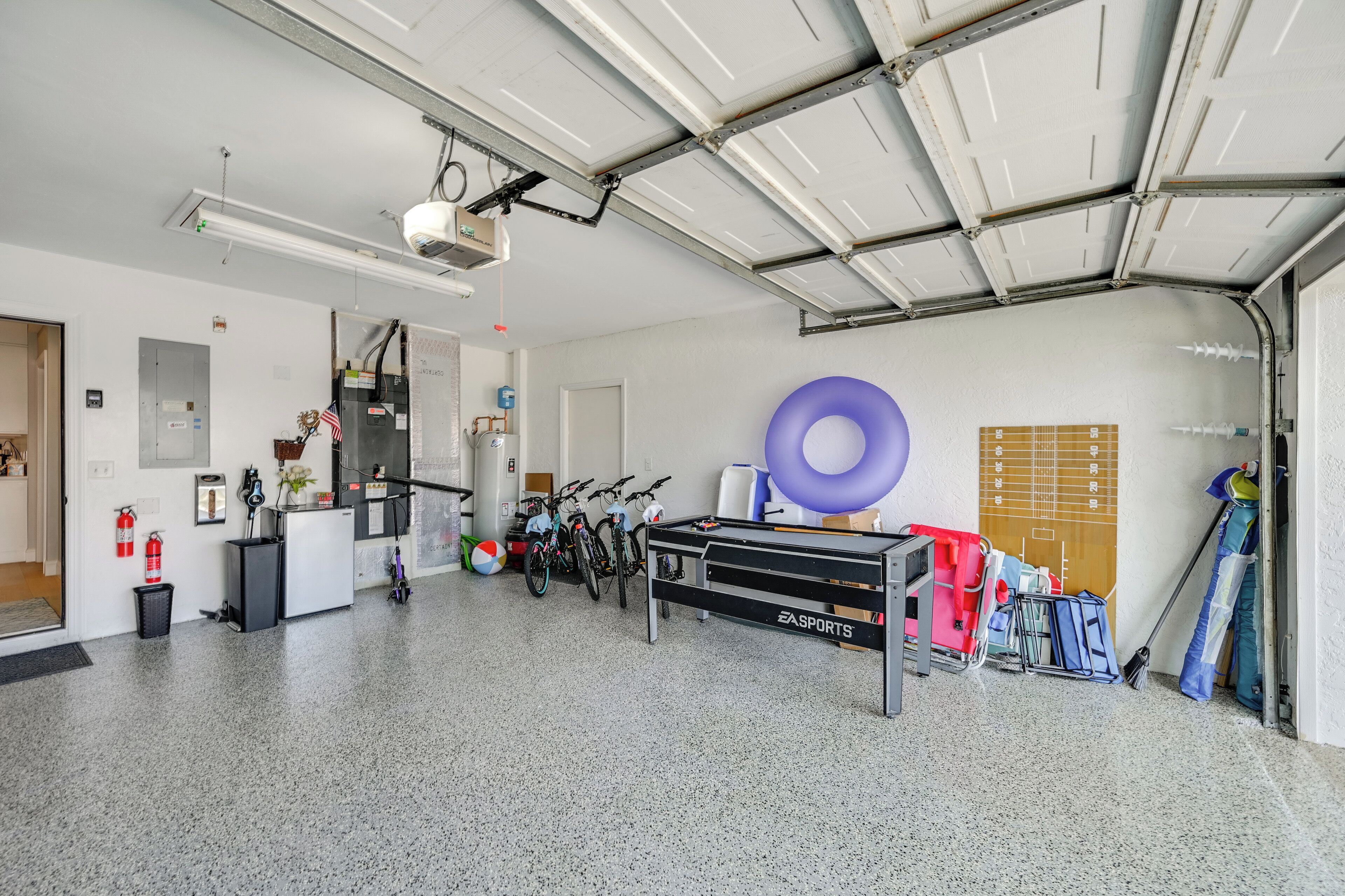 A spacious indoor area with a pool table, bicycles, and sports equipment.