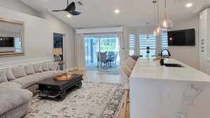 A modern kitchen with a central island, a dining area with a sofa and coffee table, and a large mirror on the wall. - Naples Escape w/ Private Pool 5 Mi to Beach (Naples)