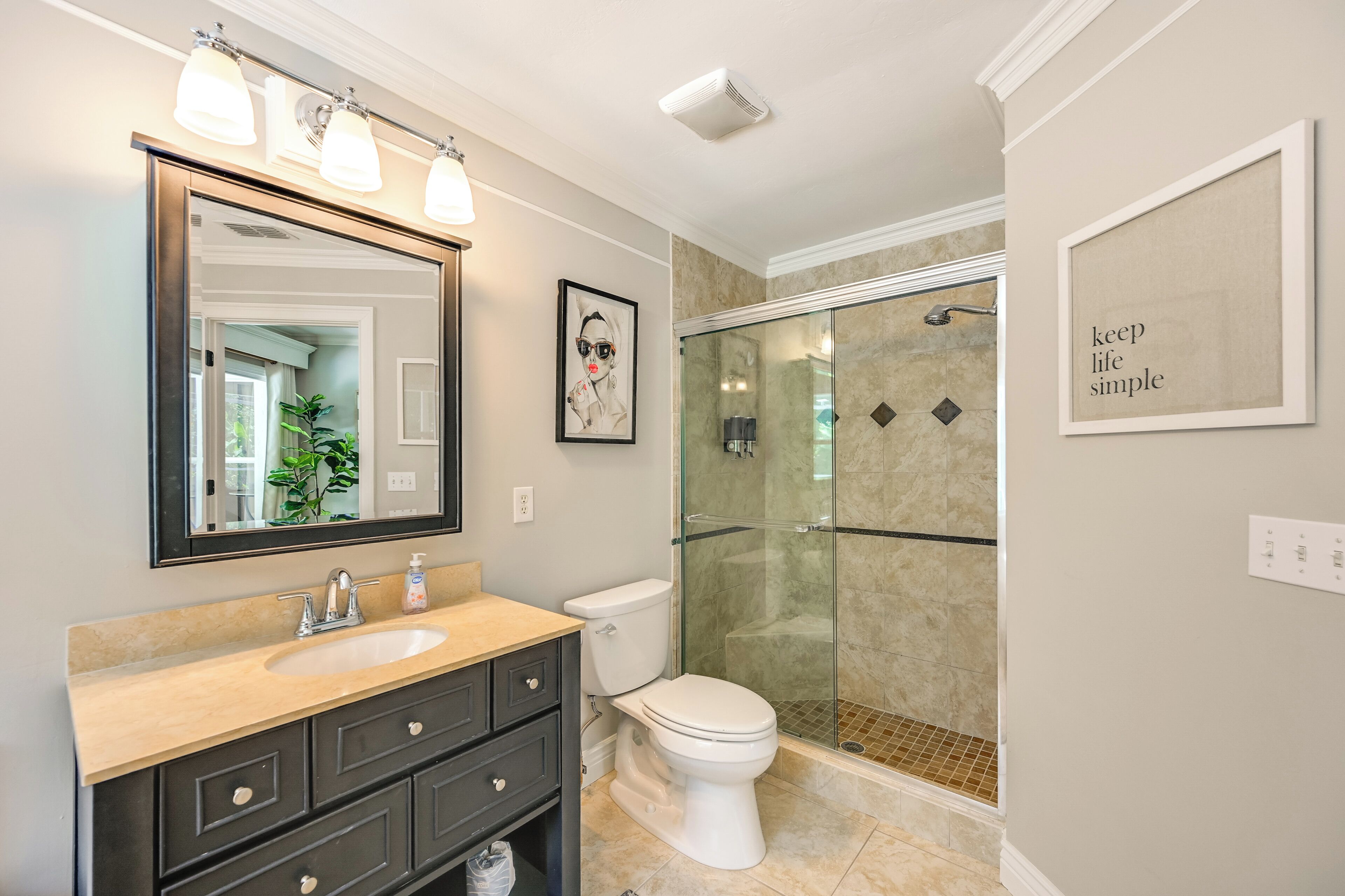 A bathroom with a large mirror, a sink, a toilet, and a glass shower enclosure.
