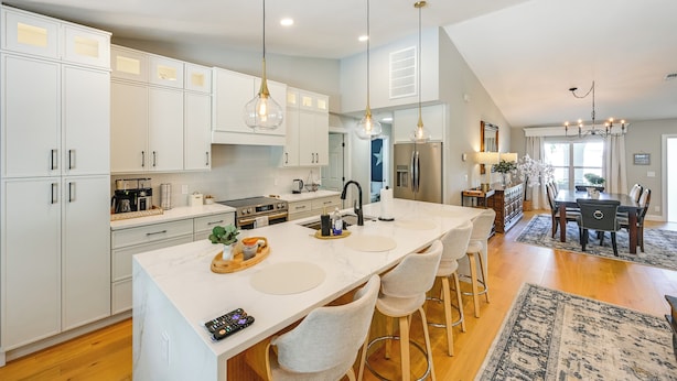 A modern kitchen with white cabinets, a large island with bar stools, and pendant lighting. - Naples Escape w/ Private Pool 5 Mi to Beach (Naples)