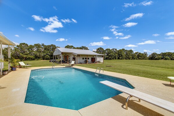 A rectangular swimming pool with a white deck and a lounge chair.
