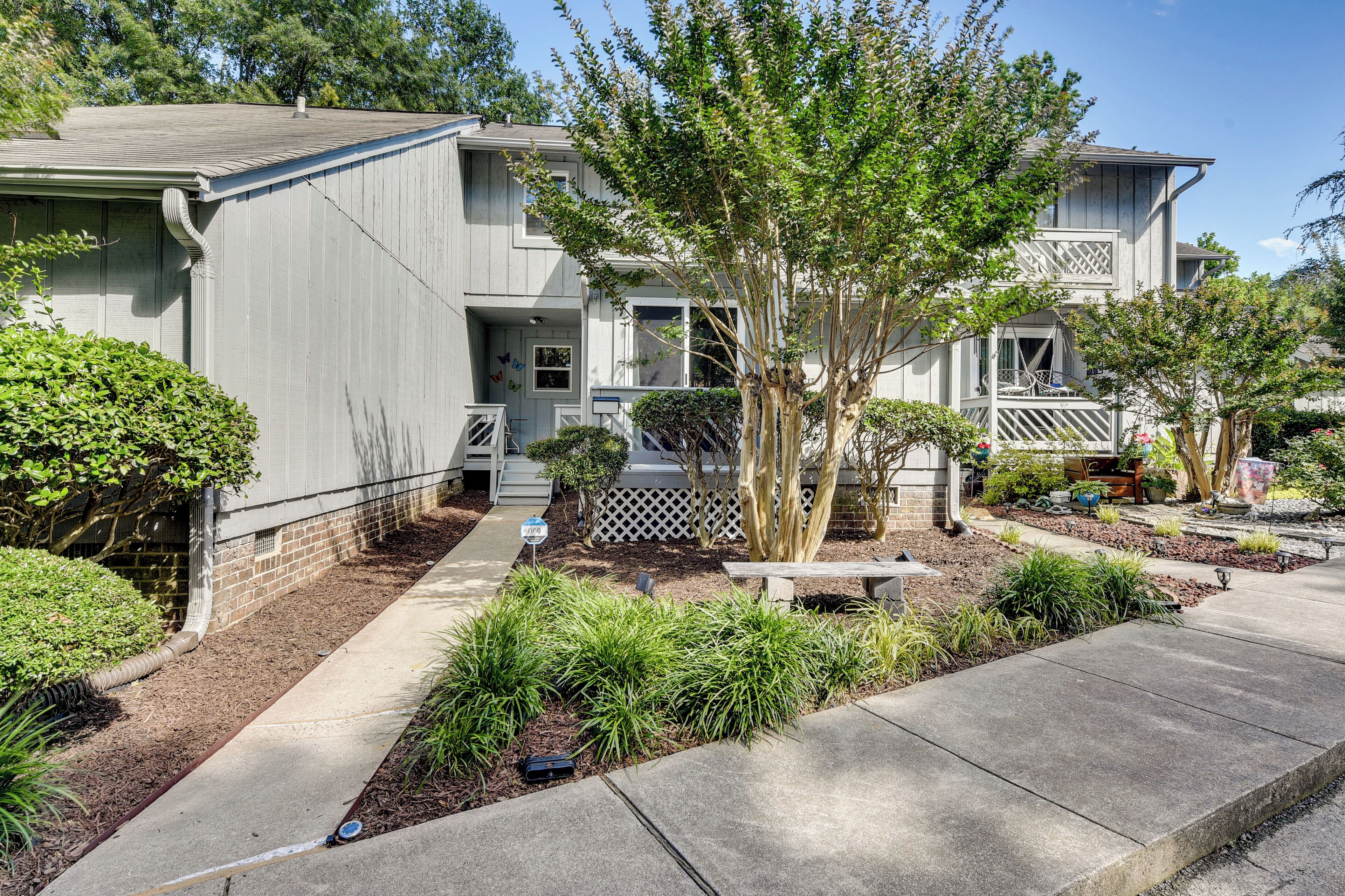 A two-story residential building with a covered patio and a small garden area.