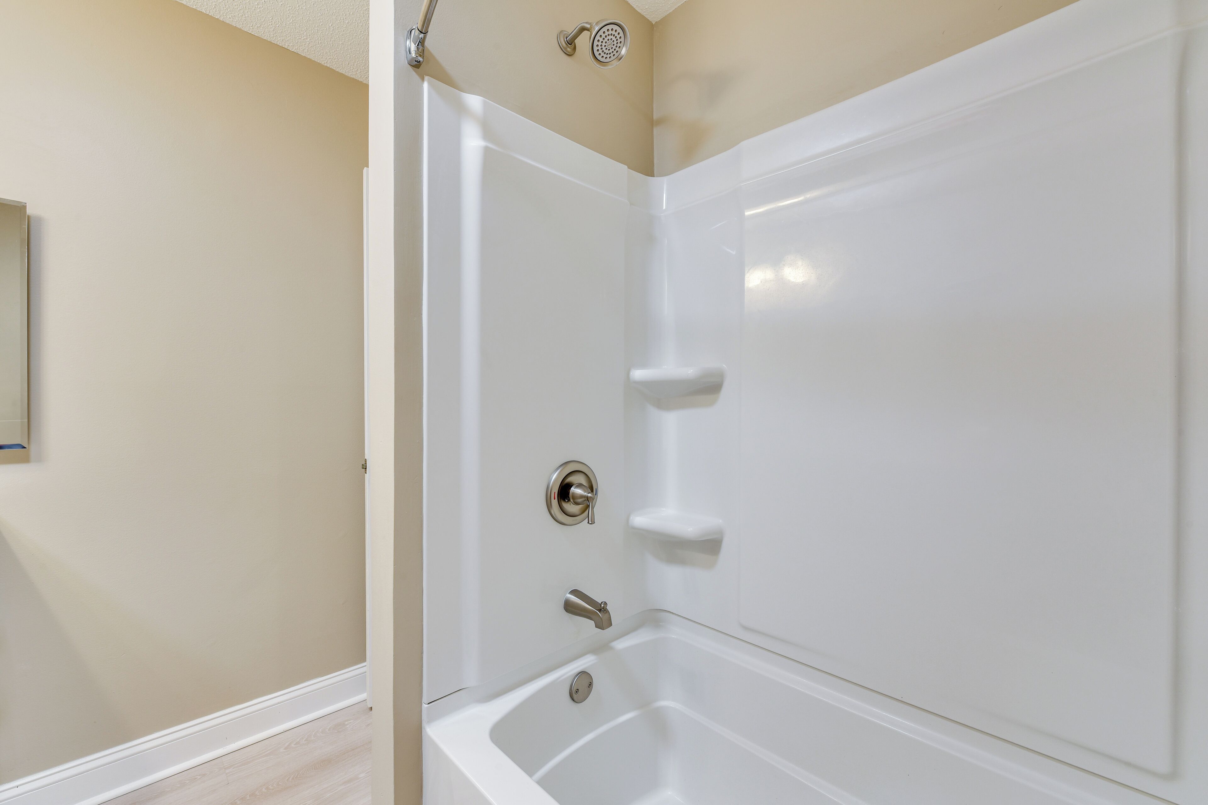 A corner of a bathroom with a bathtub, a showerhead, and a toilet.