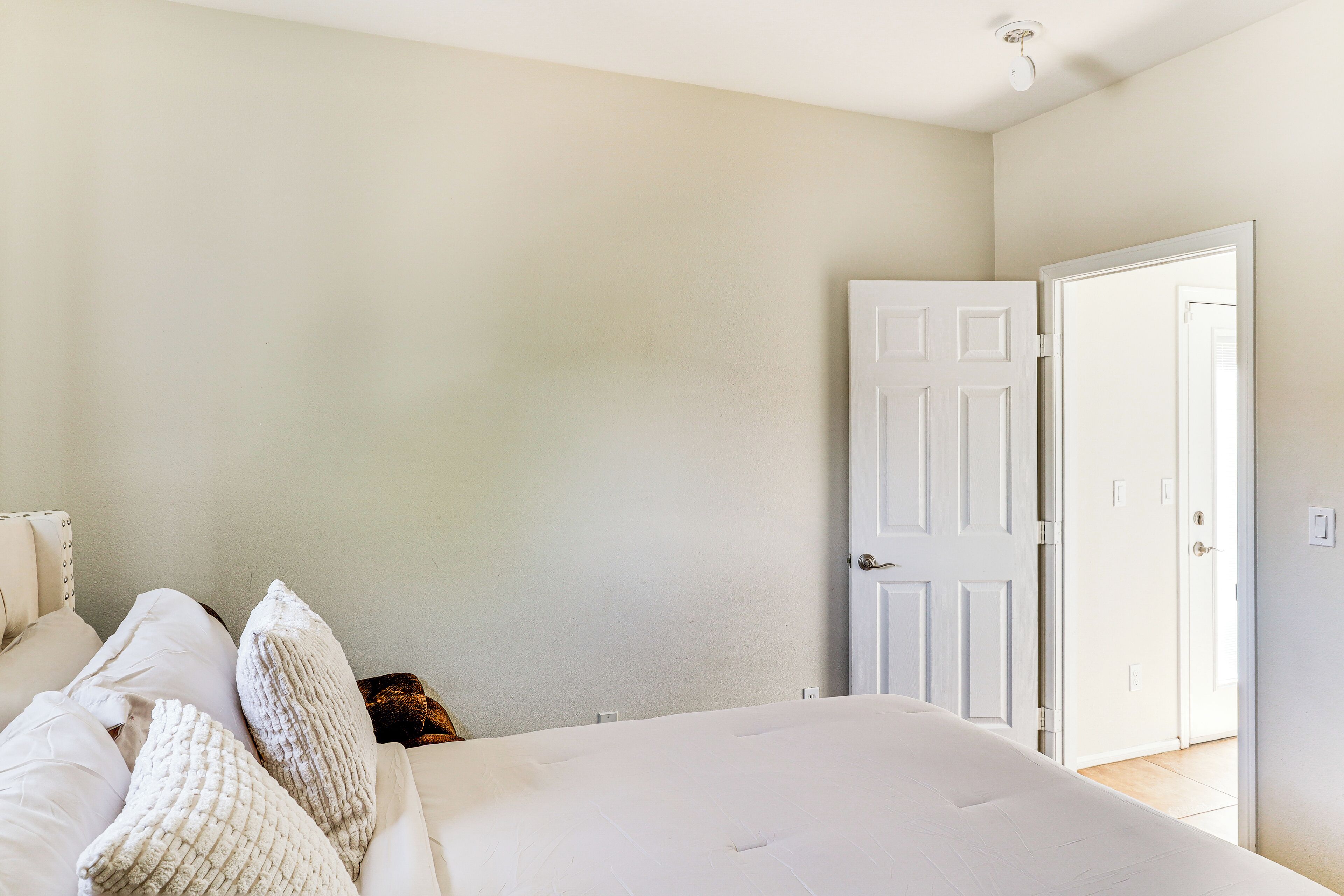 A bedroom with a bed, white walls, and a closed door.
