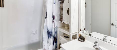 A bathroom with a bathtub, toilet, and a sink with a mirror.