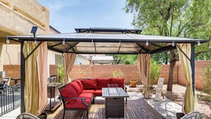 A covered patio area with a red sofa, a table, and chairs. - North Las Vegas Home w/ Hot Tub - 14 Mi to Strip! (North Las Vegas)