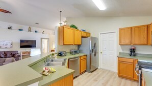 A compact kitchen with wooden cabinets, a stainless steel refrigerator, and a built-in oven. - Family Home w/ Pool: Visit Disney & Orlando Parks! (Davenport)