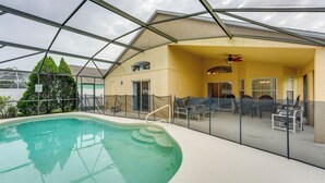 An indoor swimming pool with a glass enclosure, a covered patio area with seating, and a building with a yellow exterior. - Family Home w/ Pool: Visit Disney & Orlando Parks! (Davenport)