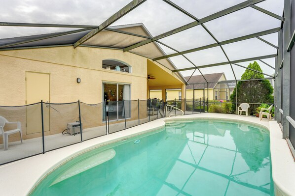 Une piscine intérieure dotée d’un toit en verre, entourée d’une clôture et jouxtant un bâtiment muni d’une porte et de fenêtres.