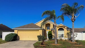 A residential house with a garage, a small front yard, and a palm tree. - Family Home w/ Pool: Visit Disney & Orlando Parks! (Davenport)