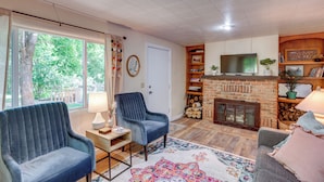 A living room with a fireplace, a television, and a large window with curtains. - Hike On-site: Mountain-view Hideaway in Durango (Durango)