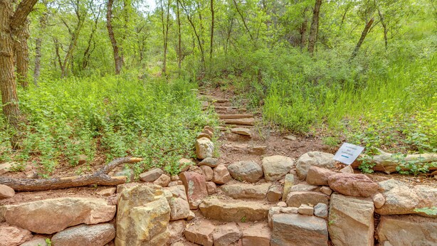 A natural stone pathway through a forested area with a sign indicating a trail. - Hike On-site: Mountain-view Hideaway in Durango (Durango)