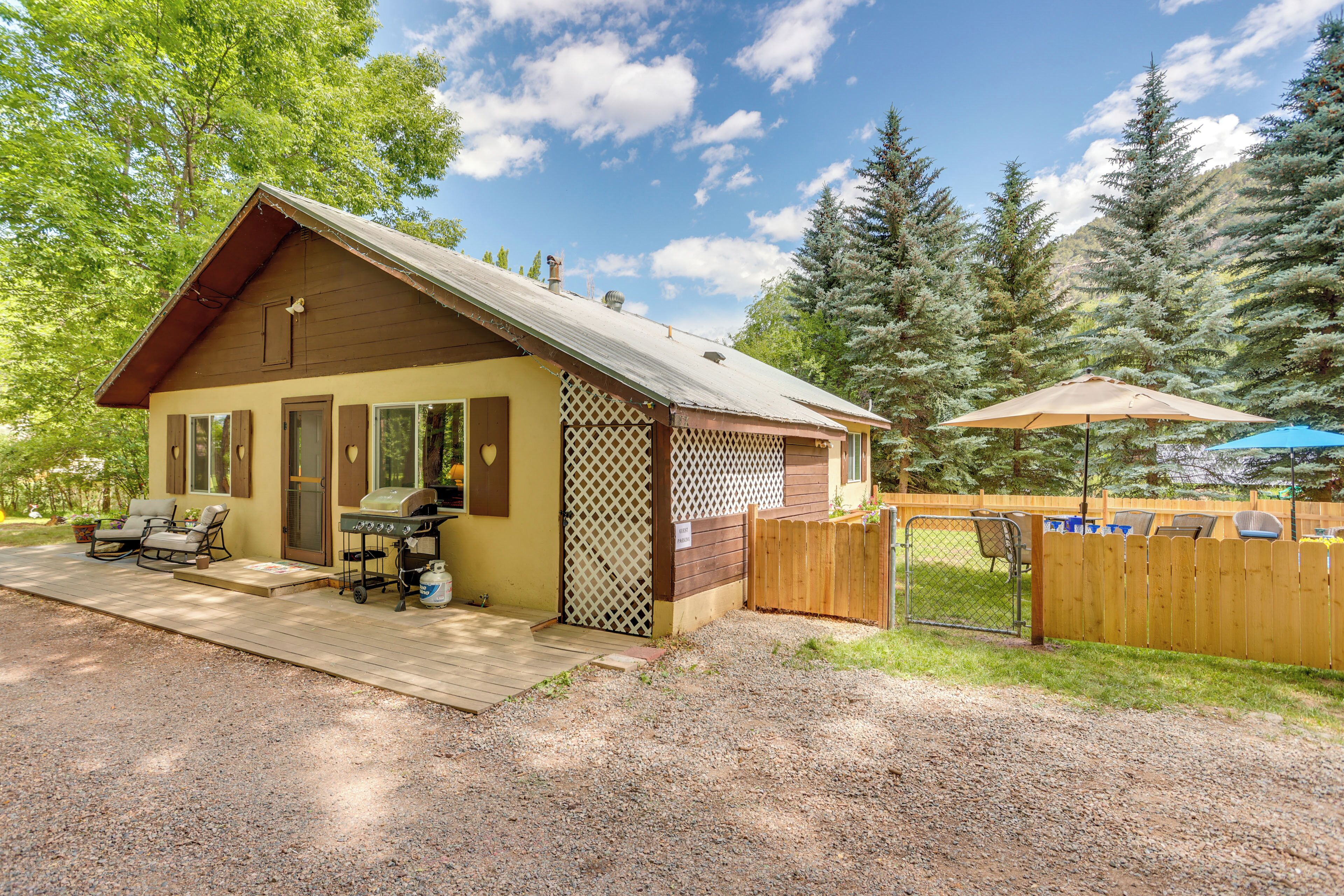 A small cabin with a deck, outdoor grill, and patio furniture.
