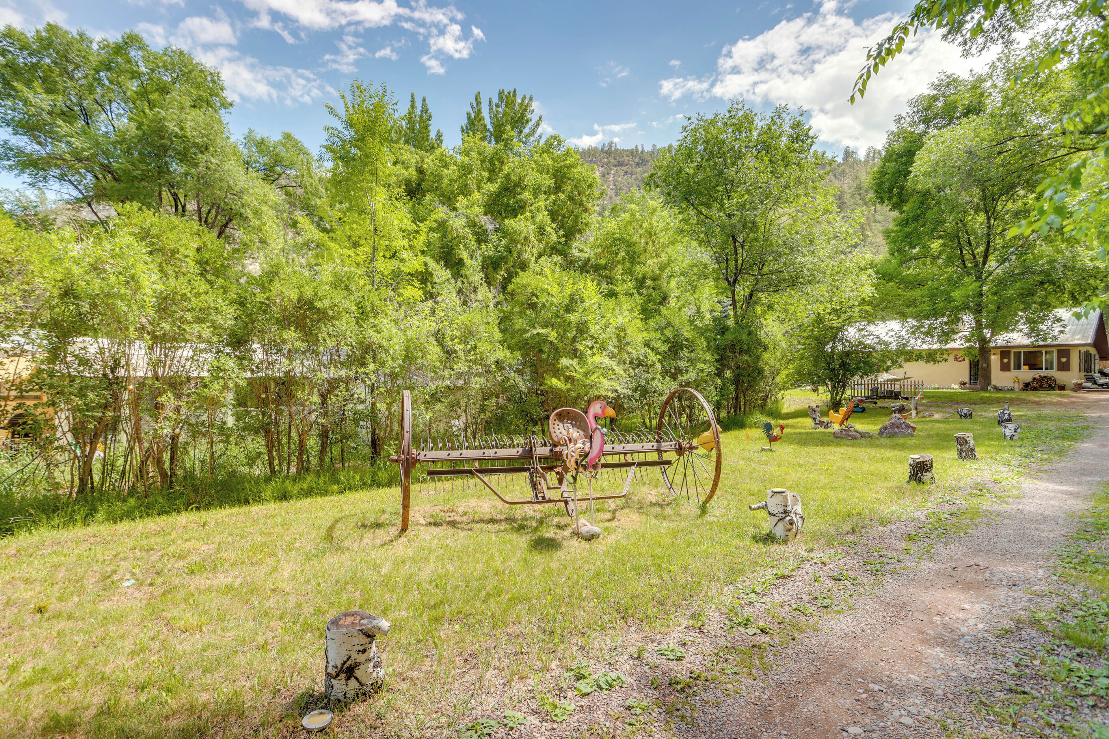 A rustic outdoor area with a wooden bench, a bird sculpture, and a rustic fence.