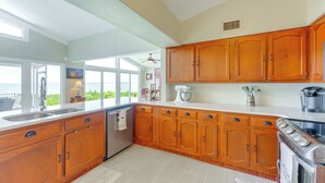 A kitchen with wooden cabinets, a stainless steel sink, and a large window overlooking a scenic view. - Family Home w/ Stunning Water Views in Tavares! (Tavares)