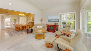 A spacious living room with a dining area, a sofa set, and a painting of a sailboat on the wall. - Family Home w/ Stunning Water Views in Tavares! (Tavares)