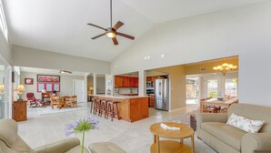 A spacious living room with a sofa, coffee table, and a dining area with chairs and a kitchen in the background. - Family Home w/ Stunning Water Views in Tavares! (Tavares)