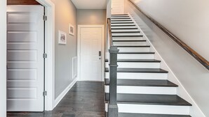 Un escalier avec des marches en bois foncé et une rampe en bois, menant à une porte blanche située en haut.