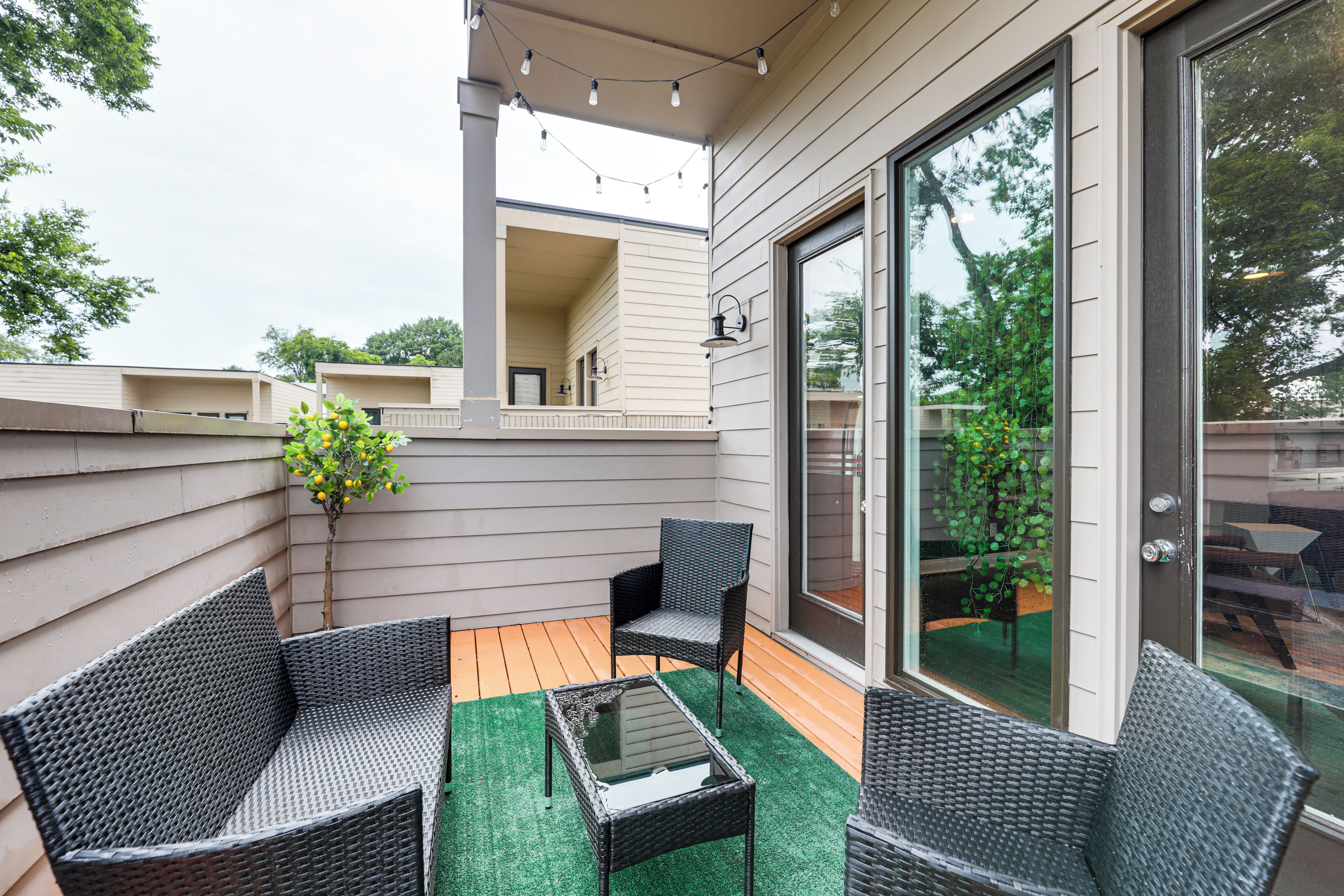 A covered patio with wicker furniture, a glass door leading to a backyard, and a small table.