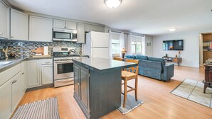 A modern kitchen with a central island, stainless steel appliances, and a dining area with a blue sofa.