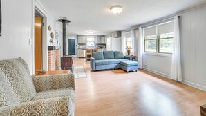 A spacious living room with a blue sectional sofa, a patterned armchair, and a wooden floor.