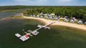 Vue aérienne d’un complexe de résidences de vacances au bord d’un lac, comprenant plusieurs maisons, un quai et des bateaux.