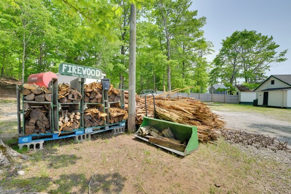 A woodpile area with a sign reading "Firewood $6 on 2/810".