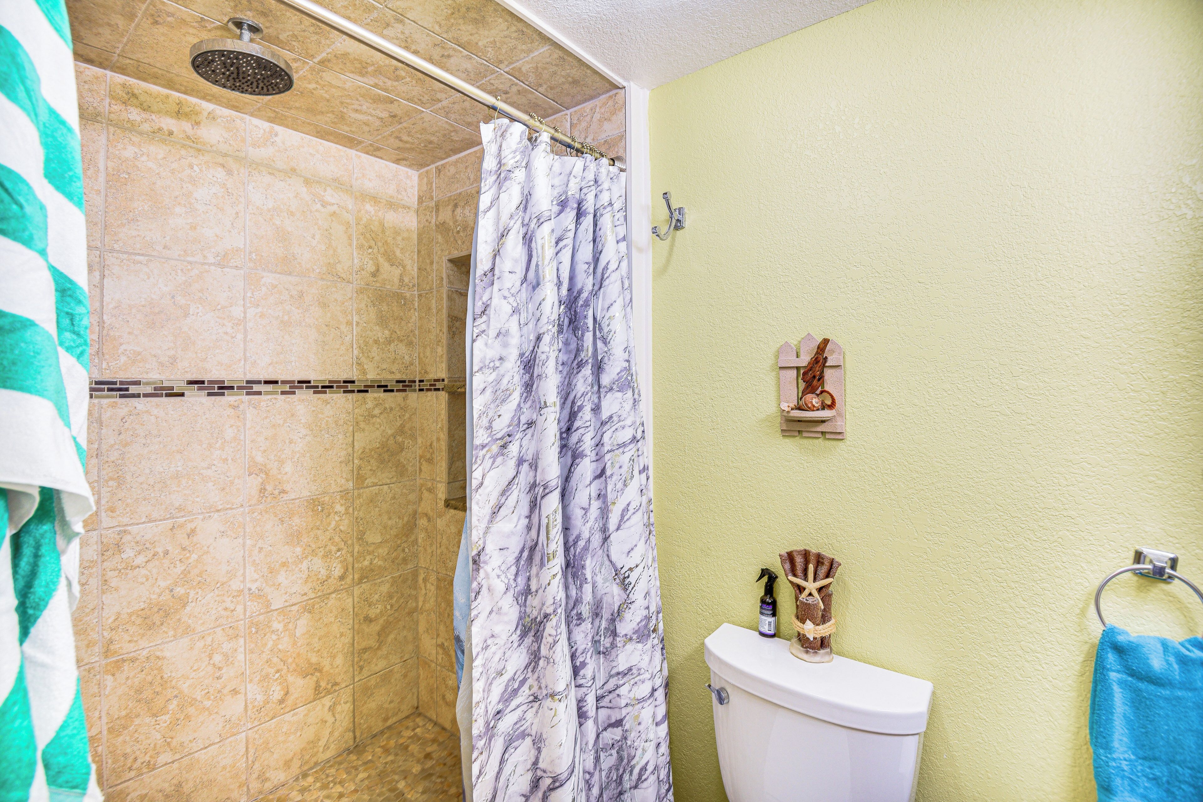 A bathroom with a shower, toilet, and a towel rack.