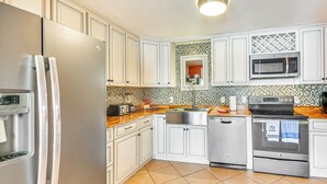 A modern kitchen with white cabinets, a stainless steel refrigerator, a microwave, an oven, and a dishwasher.