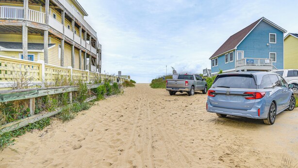 A beachside building with a wooden deck and a vehicle parked in front.