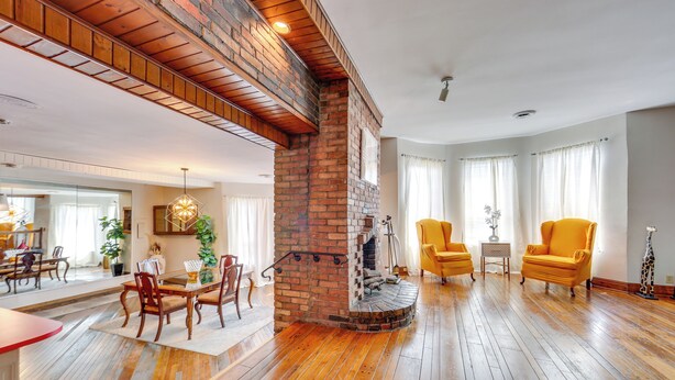 A spacious living room with hardwood floors, a brick fireplace, and yellow armchairs. - 2 Mi to Dtwn Pittsburgh: Family-friendly Townhome! (Pittsburgh)