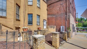 A two-story brick building with a metal fence, potted plants, and a clear sky. - 2 Mi to Dtwn Pittsburgh: Family-friendly Townhome! (Pittsburgh)