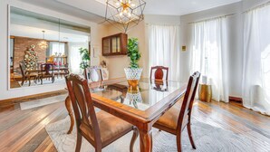 A dining area with a glass table, wooden chairs, a geometric pendant light, and a large mirror reflecting the room. - 2 Mi to Dtwn Pittsburgh: Family-friendly Townhome! (Pittsburgh)