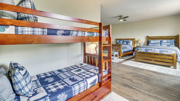 A bunk bed room with a wooden headboard, a lower bed with a quilt, and a desk with a lamp. - 2 Mi to Angel Fire Resort: Luxury Condo w/ Balcony (Angel Fire)