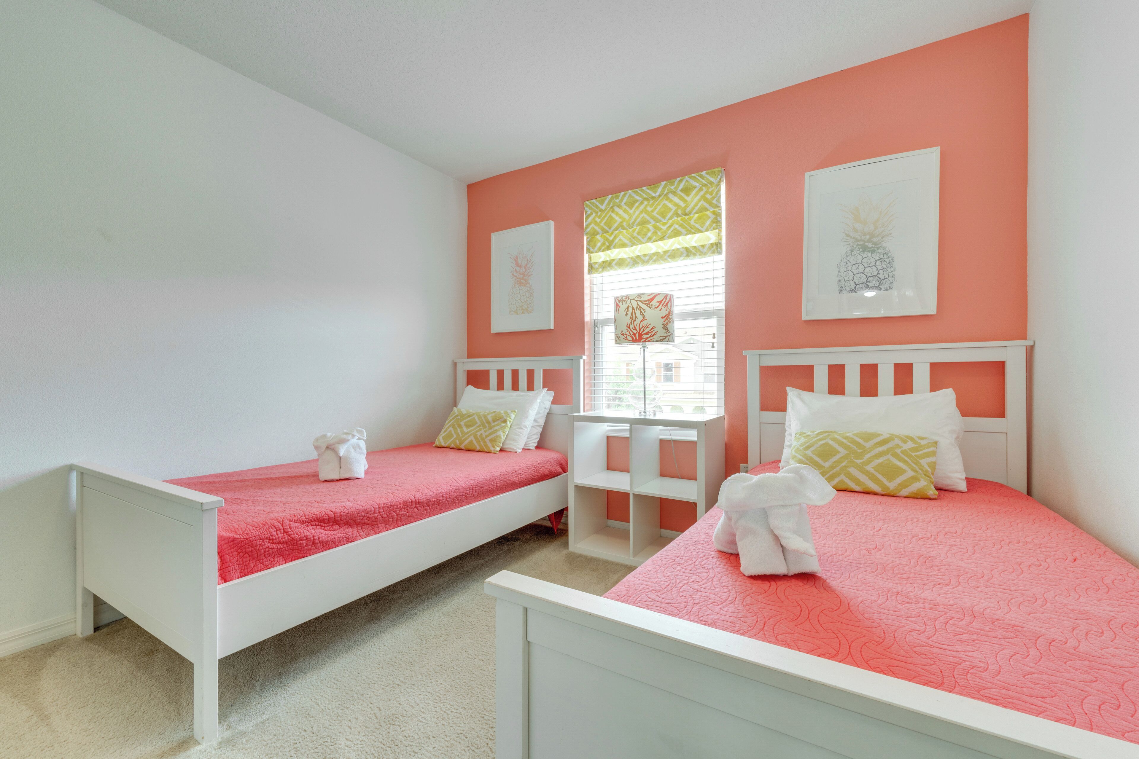 A bedroom with two single beds, a small table, and a window with blinds.