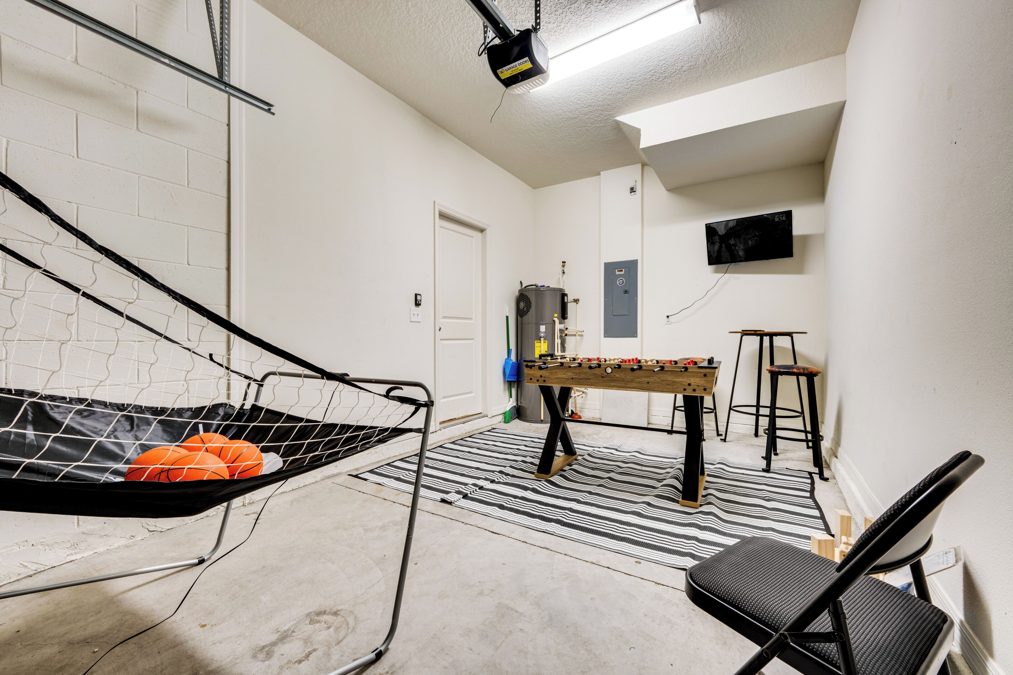 Ein Zimmer mit Futonbett, Kicker und Wandfernseher.