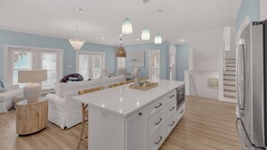 A modern kitchen with white cabinetry, a central island, and pendant lighting.