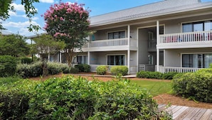 A multi-story hotel with balconies, a well-maintained garden, and a clear sky. - Minutes to Beach & Shops on 30A + Free tickets: Bikes, Dolphin Cruise & More! (Santa Rosa Beach)