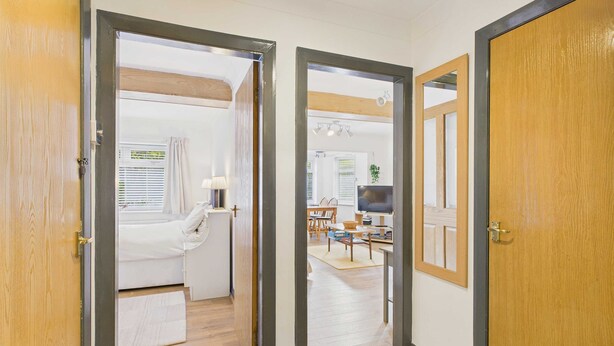 A hallway leading to a bedroom with a bed, a desk, and a chair. - Host Stay Look Flat (Scarborough)