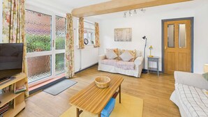 A living room with a TV, sofa, and a wooden coffee table. - Host Stay Look Flat (Scarborough)