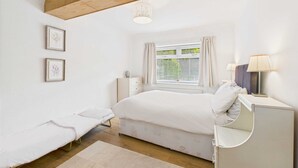 A bedroom with a bed, bedside table, lamp, and a window with curtains. - Host Stay Look Flat (Scarborough)