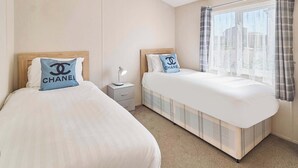 A hotel room with two beds, a nightstand with a lamp, and a window with curtains. - Host Stay Clearwater Willey Lodge (Sheerness)